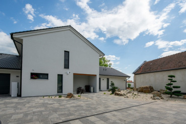 [Dvůr s dlažbou před moderní dřevostavbou na klíč]