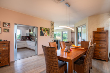 [Bungalov 4 kk s terasou - interiér, obytný prostor v přírodních tónech, průhled na moderní kuchyňskou linku.]