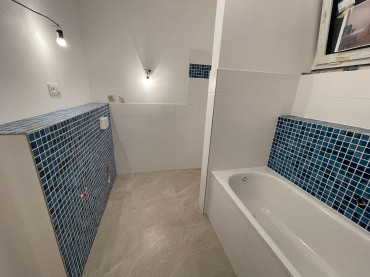 [Rodinný dům Haas, bungalov na míru, 3+kk. Koupelna s vanou, bílo-modré obložení.]