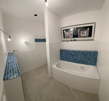 [Rodinný dům Haas, bungalov na míru, 3+kk. Koupelna s vanou, bílo-modré obložení.]