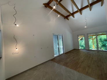 [Rodinný dům Haas, bungalov na míru, 3+kk. Interiér, obývací pokoj s otevřeným stropem, dřevěná podlaha, výhled do zahrady.]